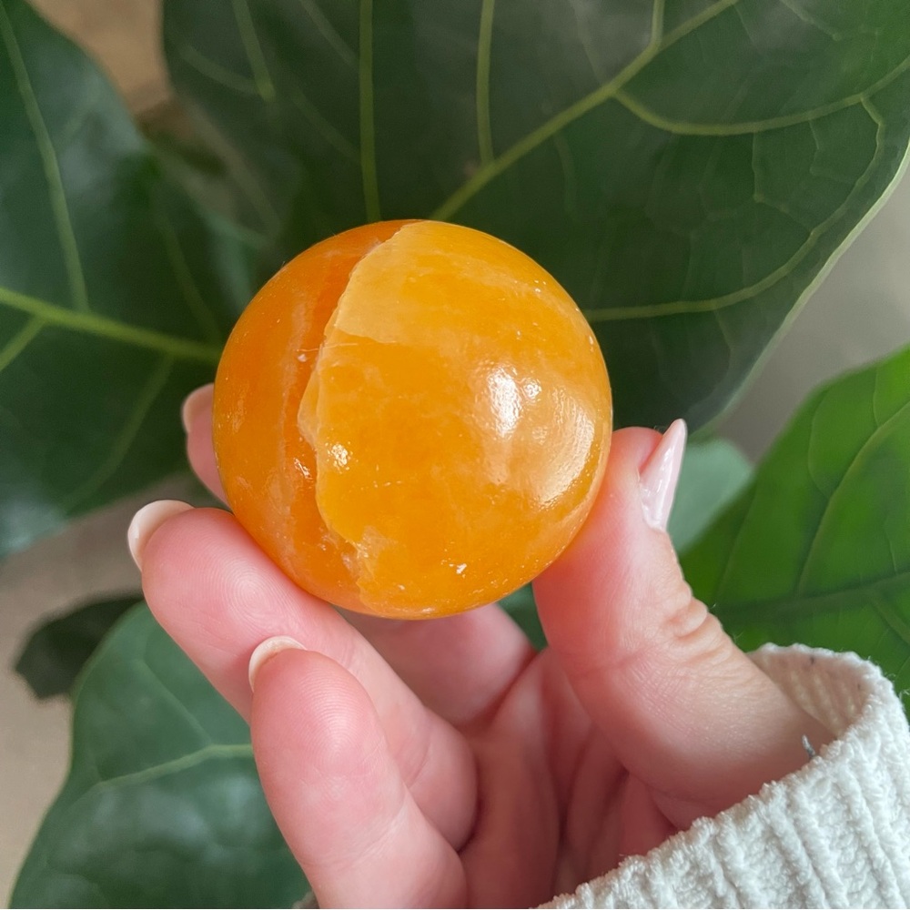 Orange calcite polished crystal sphere with stand